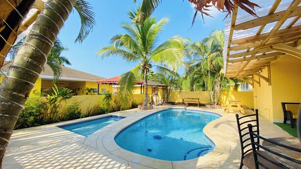 A swimming pool with two lanes, surrounded by palm trees and a covered seating area.