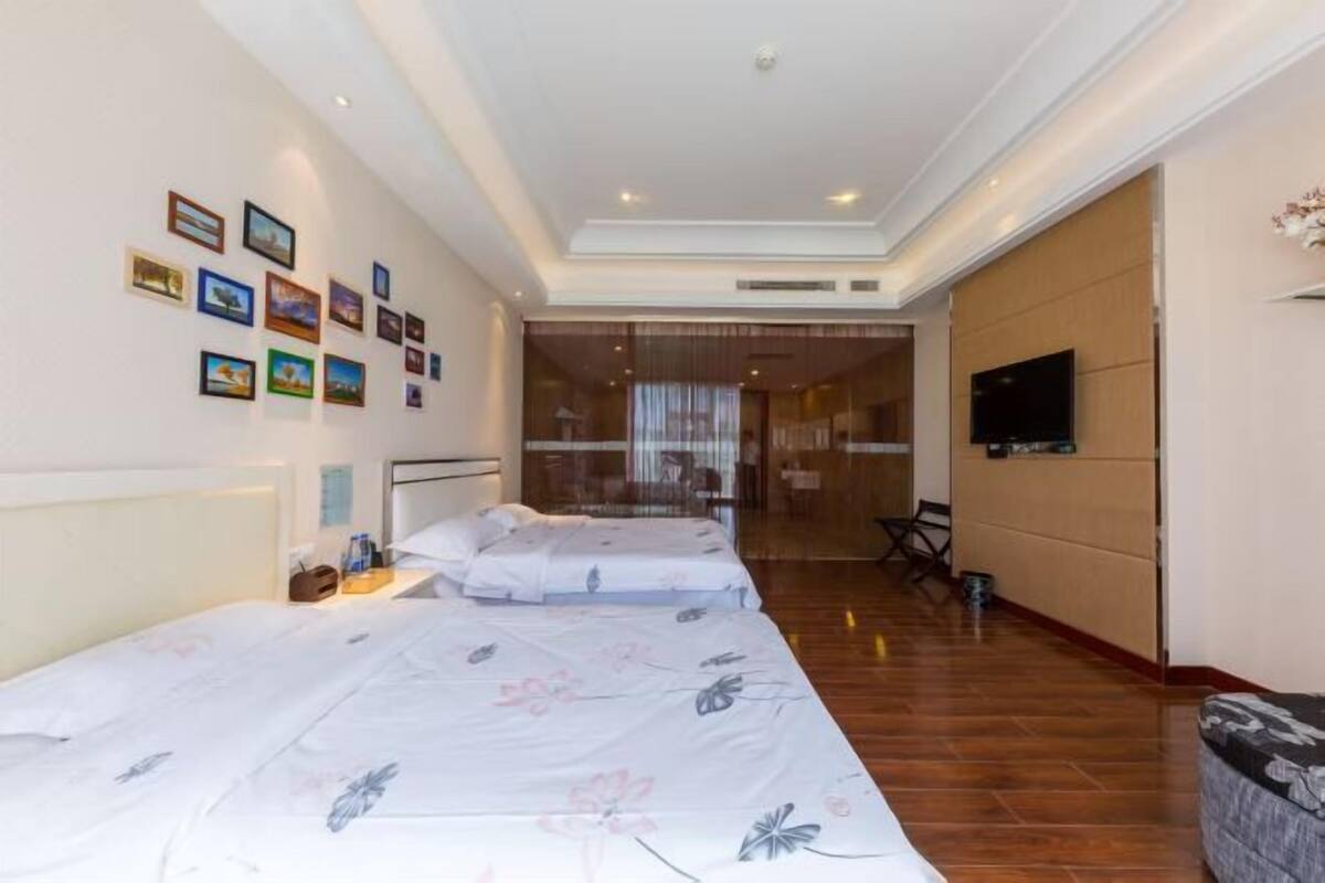 Habitación de hotel con dos camas, televisión y un muro decorado con imágenes.