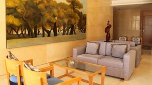 A living room with a sofa, a coffee table, and a painting of trees.