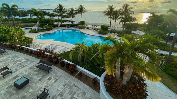Un resort con piscina, sillas de descanso y palmeras.