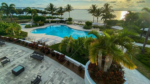 Un resort con piscina, sillas de descanso y palmeras.