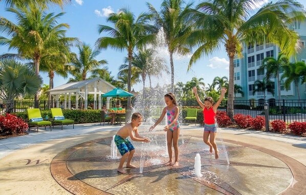 A water play area with palm trees, lounge chairs, and a covered seating area.