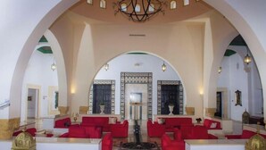 A spacious lobby with red seating, high ceilings, and a chandelier. - Hôtel Écrin hamammet  (Hammamet)