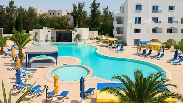 A resort pool area with sun loungers, umbrellas, and a building with multiple balconies. - Hôtel Écrin hamammet  (Hammamet)