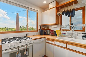 A kitchen with a gas stove, oven, and a window with a view of a tower.