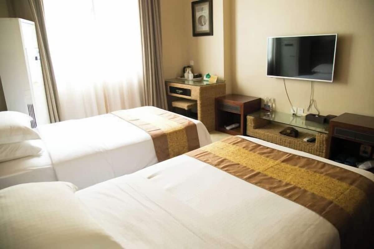 A hotel room with two beds, a TV, a desk, and a wardrobe.