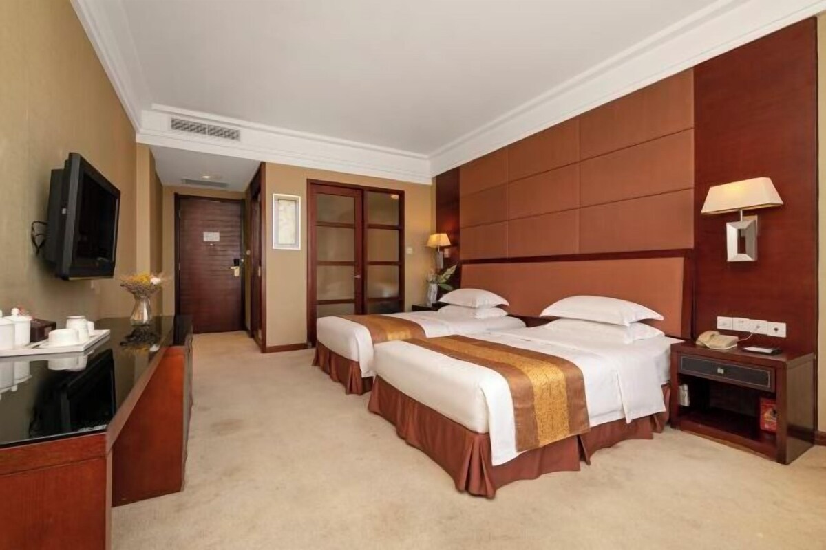 A hotel room with two beds, a desk with a TV, a lamp, and a phone.