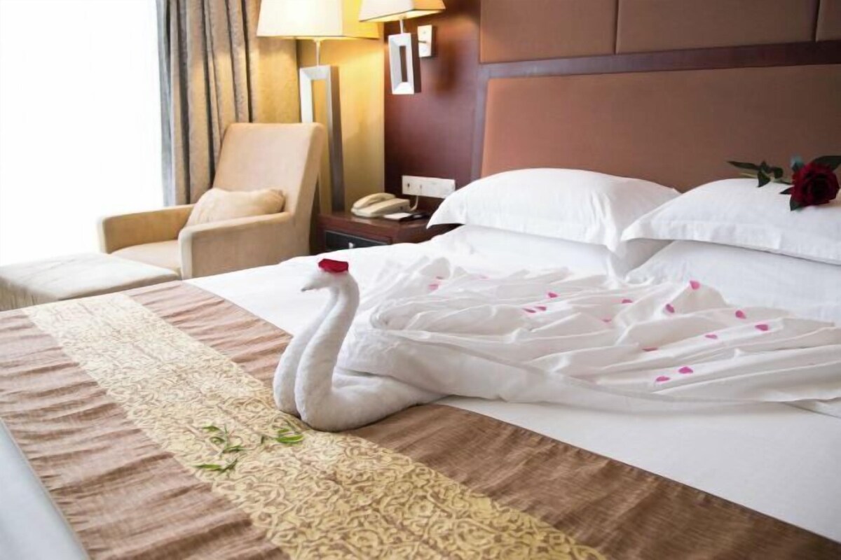 A hotel room with a bed, a chair, a nightstand, and a lamp.