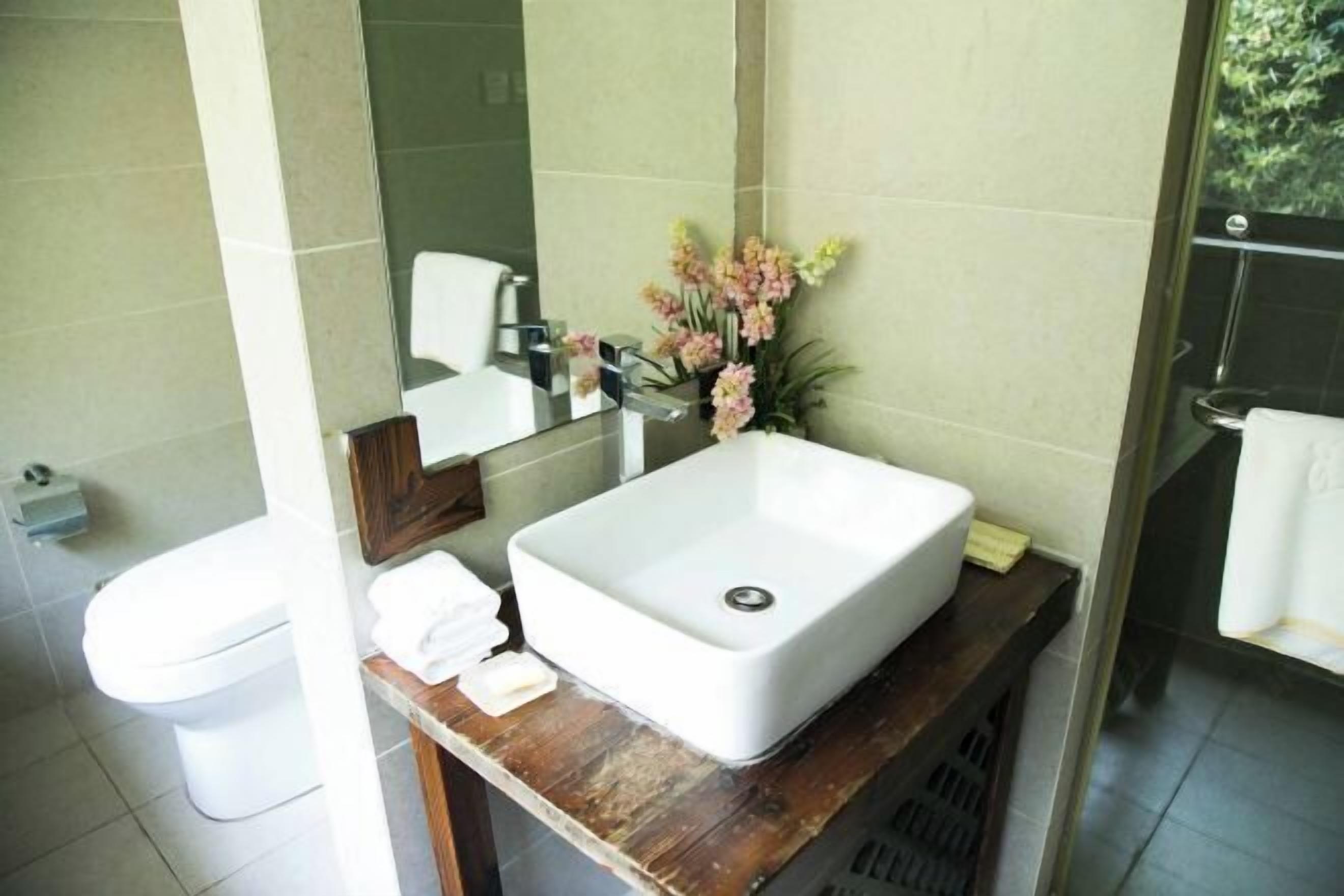 A bathroom with a white sink, mirror, and toilet.