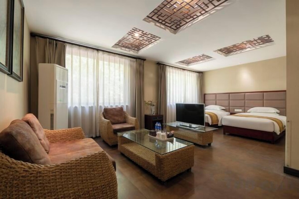A hotel room with a sofa, a television, a bed, and a glass coffee table.