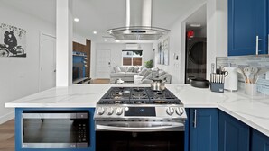 Een moderne keuken met een centraal eiland, een ingebouwde oven en roestvrijstalen apparatuur.