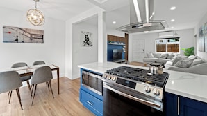 Een moderne keuken met een centraal eiland, een inbouwoven en een roestvrijstalen afzuigkap.