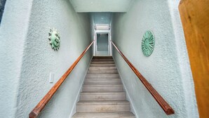 Een trap met houten leuningen, een lichtgekleurde muur en decoratieve zonmotieven.