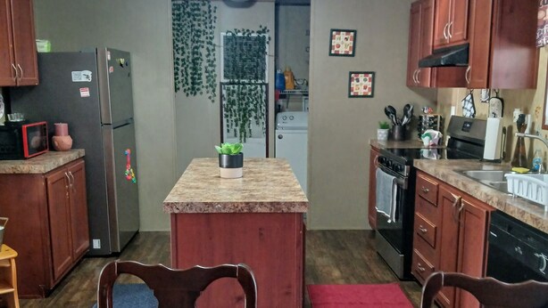 A compact kitchen with wooden cabinets, a central island, and a dining area with two chairs. - Handicap Accessible Private Spacious Beautiful Family Home 5 Acres Pet Friendly  (Homosassa)