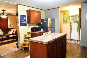 A kitchen with wooden cabinets, a refrigerator, a microwave, and a small island.