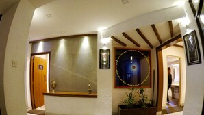 A hallway with a reception desk, a welcome sign, a decorative mirror, and a potted plant. - Marcopolo (Kathmandu)