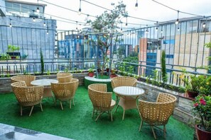 Une terrasse extérieure aménagée avec des meubles en osier et des plantes en pot.