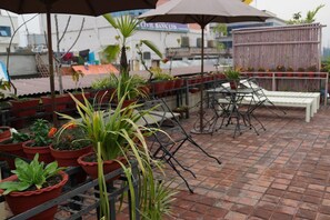 A rooftop terrace with potted plants, outdoor furniture, and a view of the cityscape. - Marcopolo (Kathmandu)