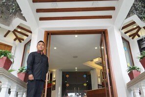 A man standing at the entrance of a building with a wooden frame and white walls. - Marcopolo (Kathmandu)