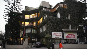 A building with ivy-covered walls and a sign for 'Coffee Travels'. - Marcopolo (Kathmandu)