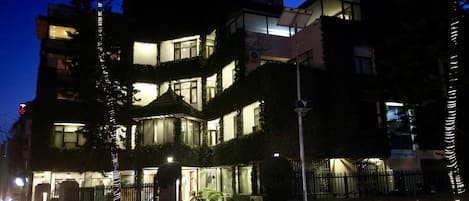 Un edificio de varios pisos con ventanas iluminadas y una entrada protegida por un portón, lo que sugiere una propiedad segura.