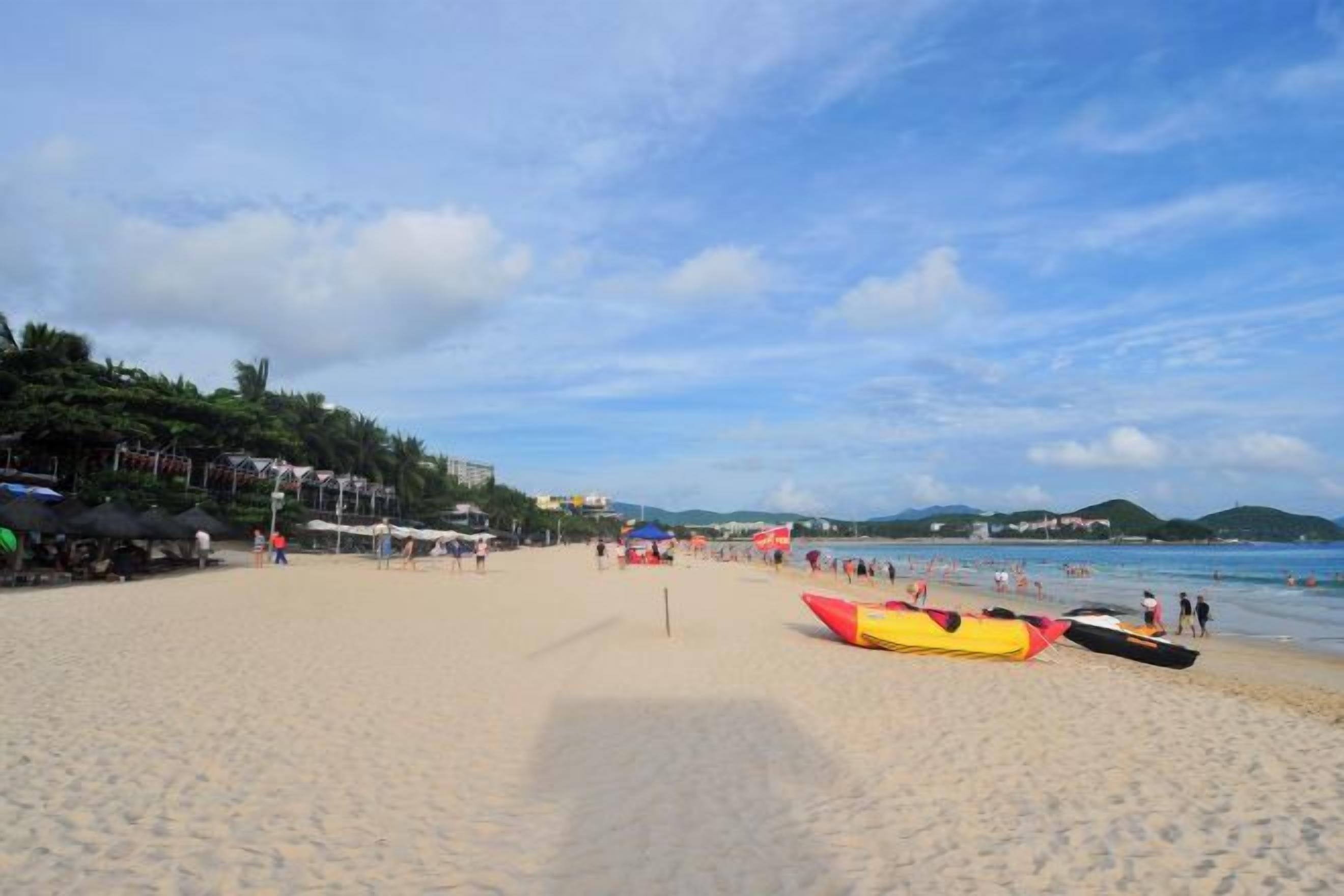 Una playa con kayaks, sombrillas y cielo despejado.