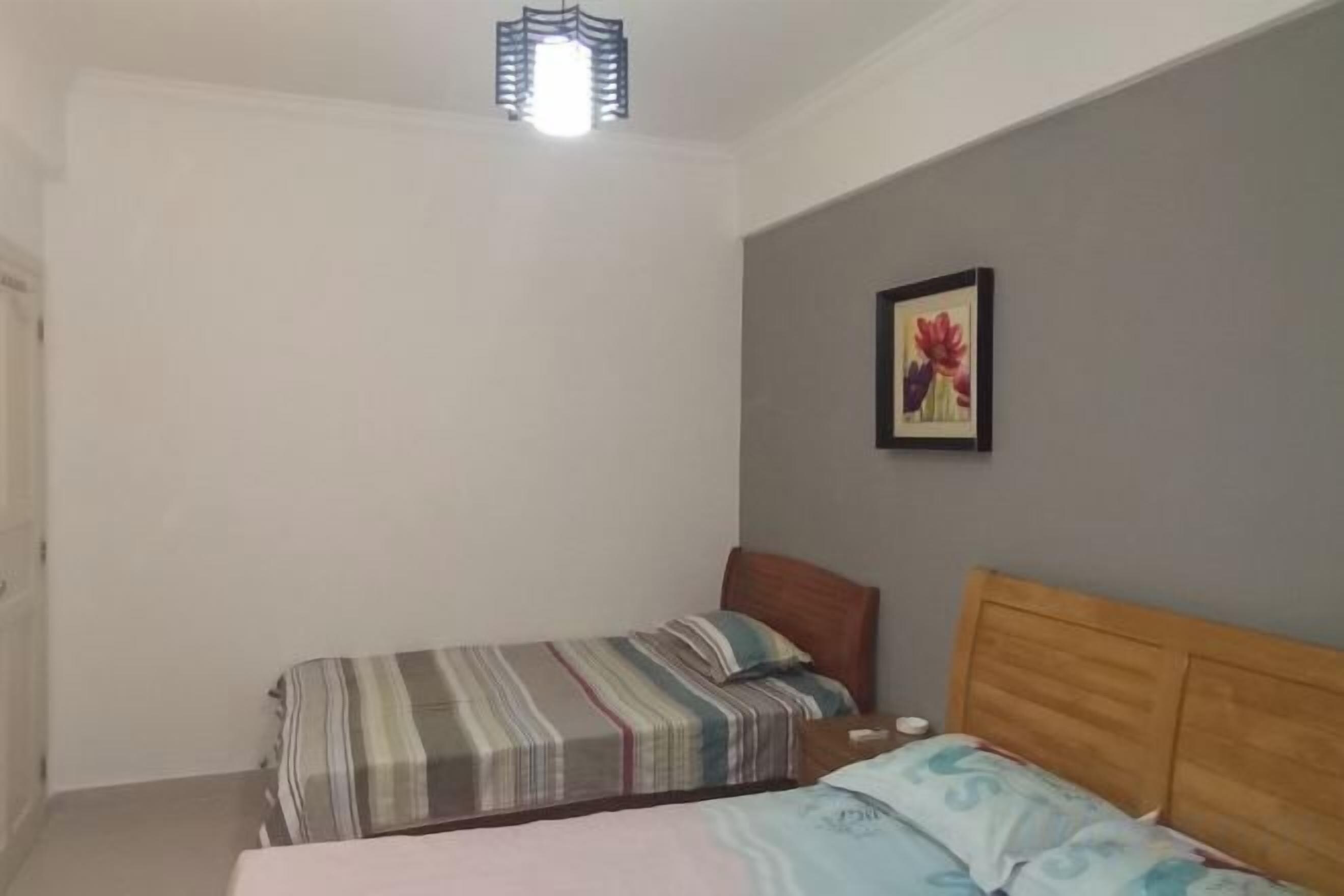 Un dormitorio con dos camas individuales, cabecero de madera, una obra de arte en la pared y una lámpara en el techo.