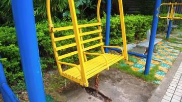 A yellow swing set with a chain and blue support structure in a park.