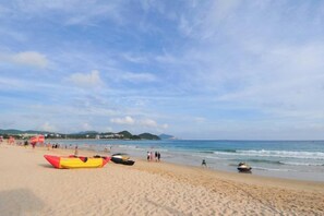 A beach with kayaks and a jet ski, a clear sky, and distant hills. - Loushanglou Seascape Motel (Sanya)