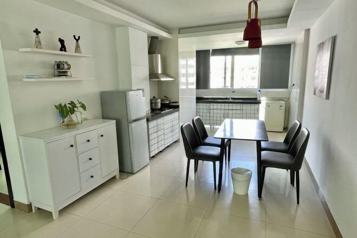 A modern kitchen with white cabinetry, a dining table with four chairs, and a red pendant light.