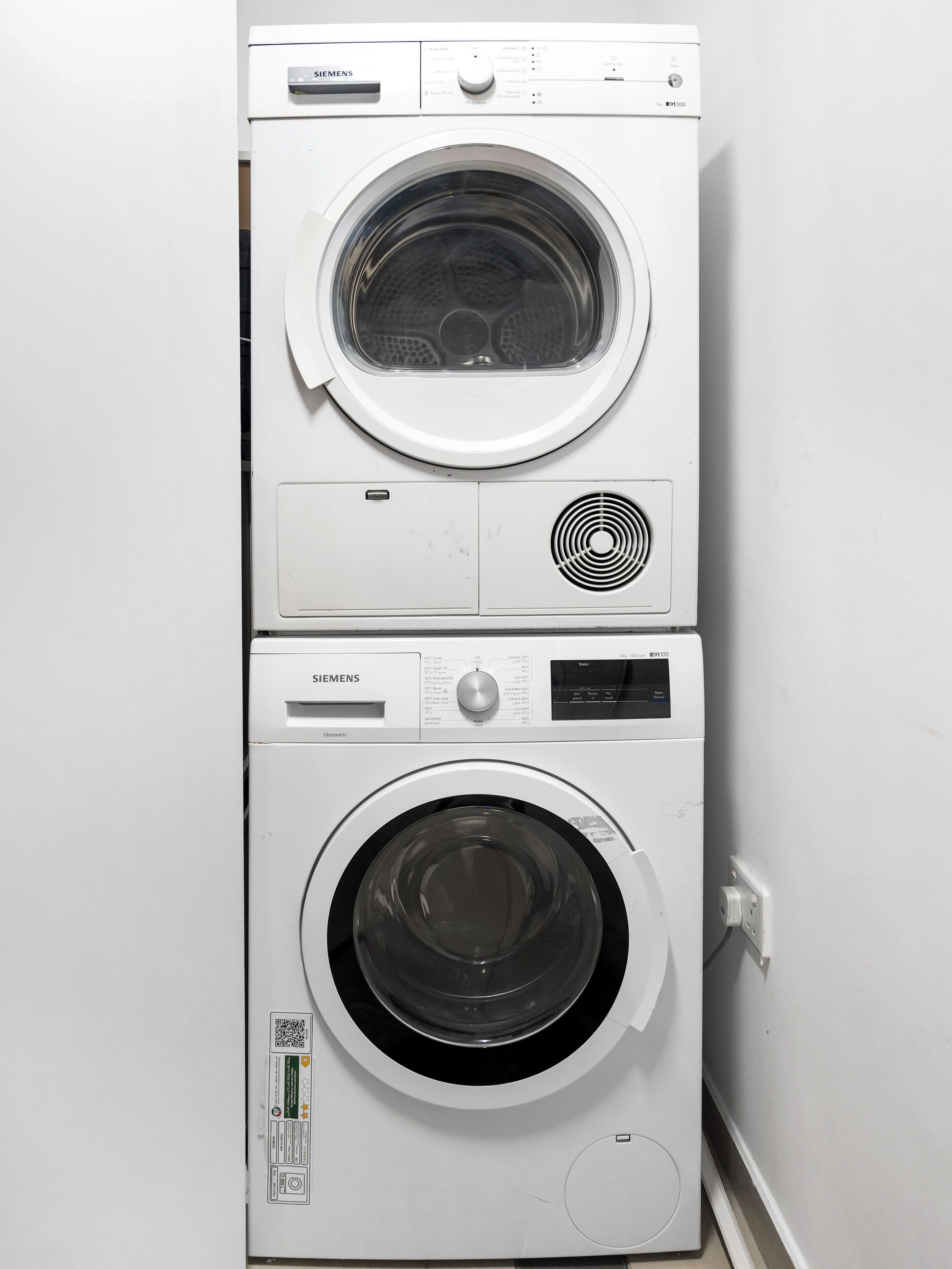 A stacked washer and dryer unit with control panels and a QR code.