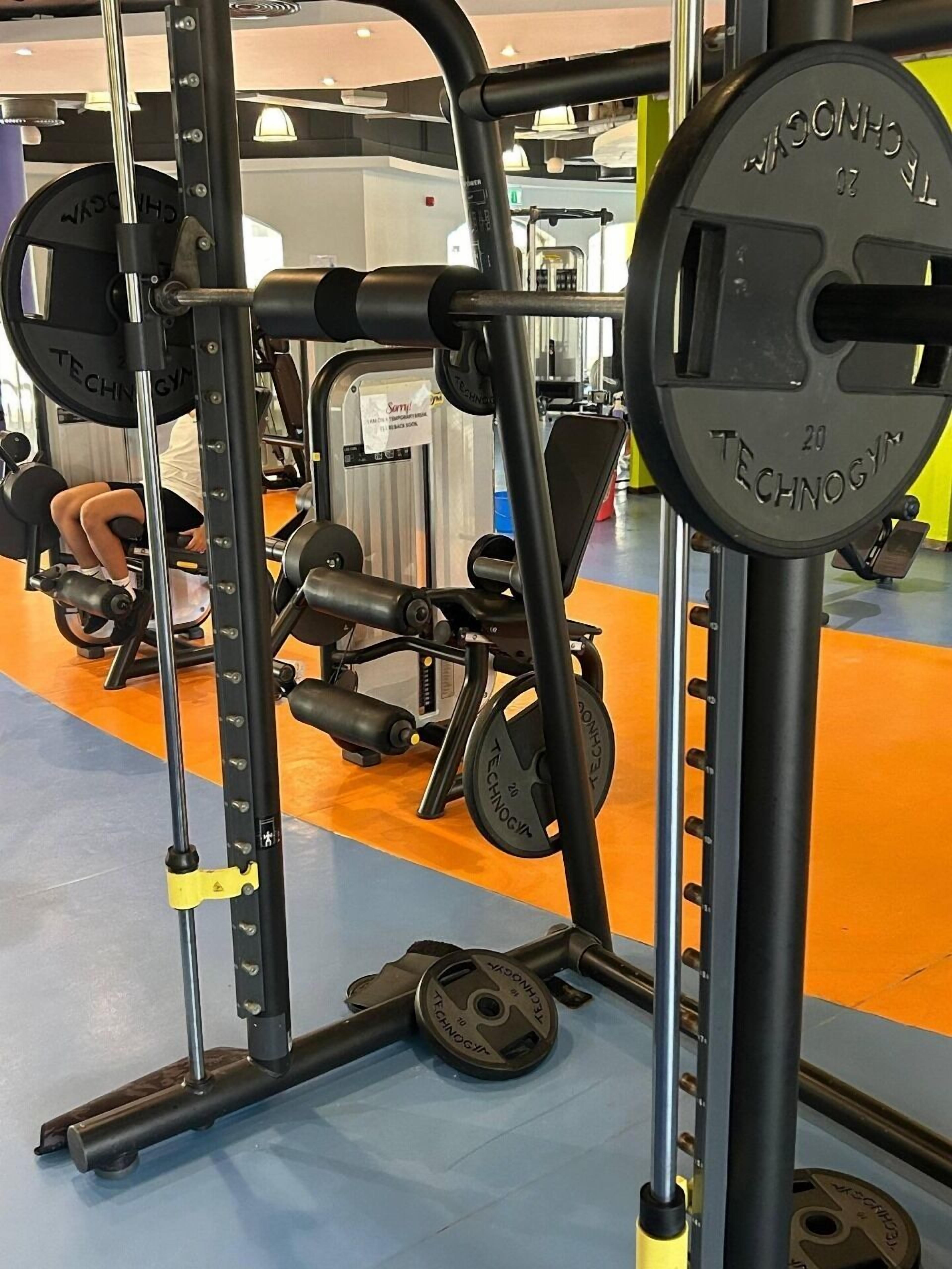 A gym with weightlifting equipment, including a squat rack and a bench press.