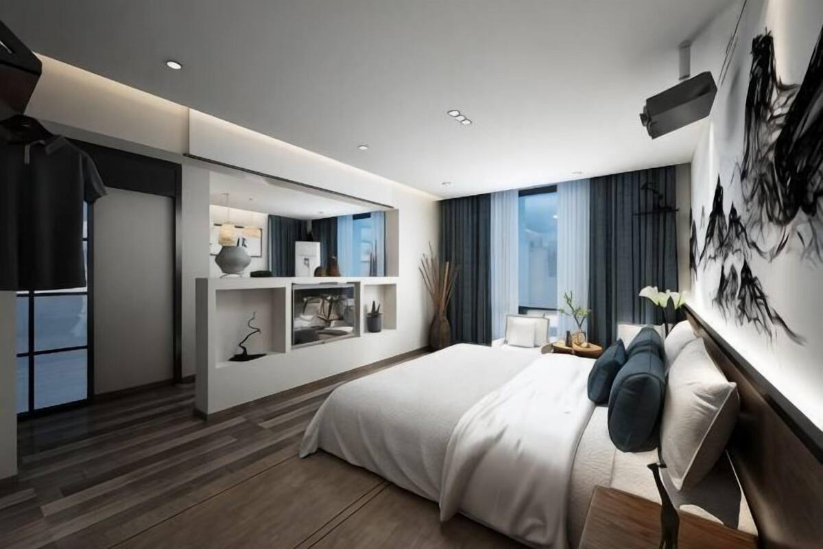 Een moderne hotelkamer met een groot bed, inbouwplanken, een bureau en een groot raam.