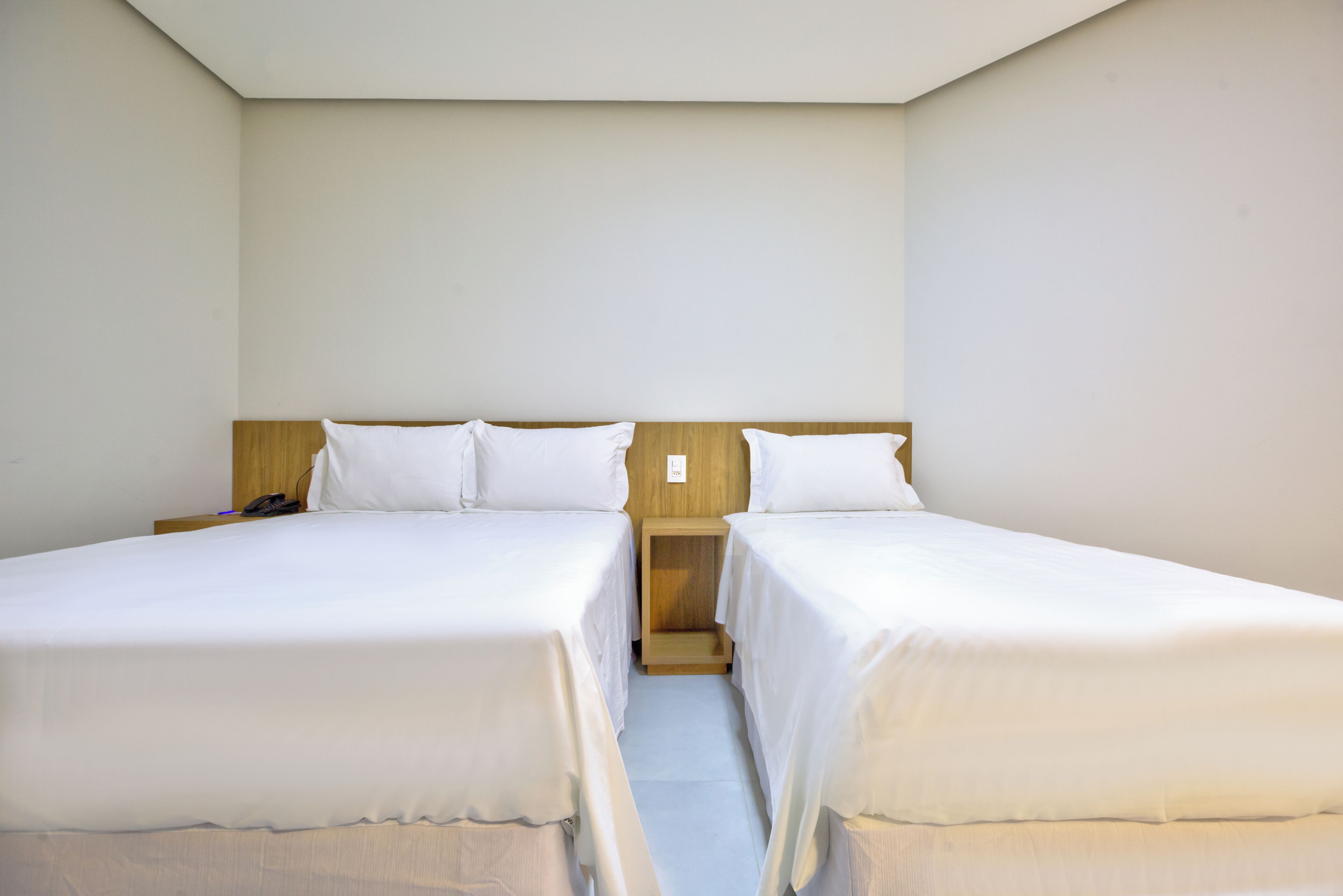 A twin room with two single beds, a wooden headboard, and a nightstand with a phone.