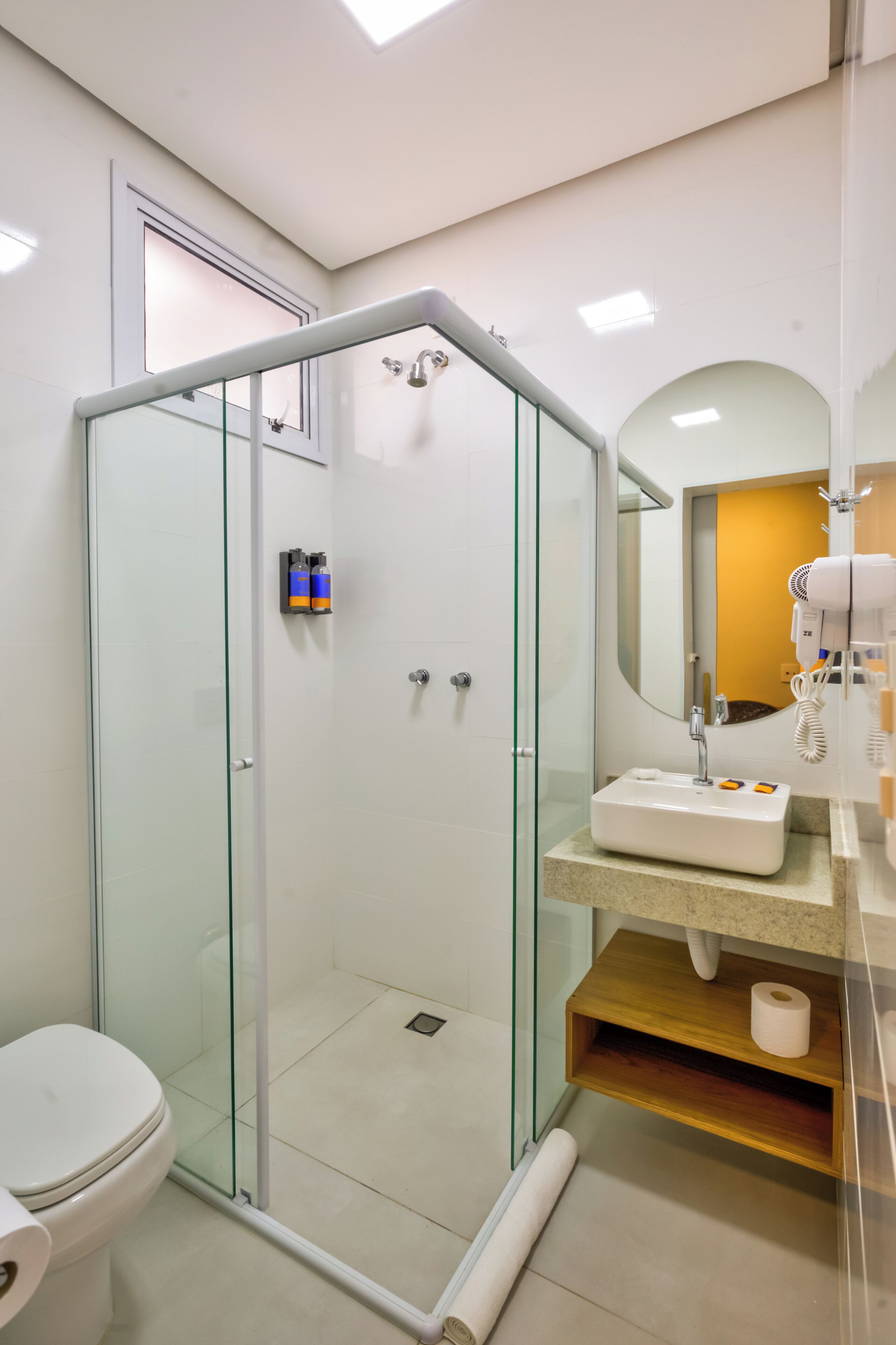 Une salle de bain moderne avec une douche à parois de verre, un lavabo blanc et un miroir.