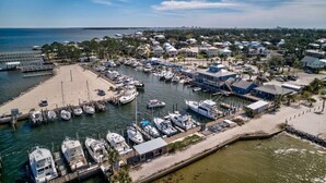 A marina with boats docked, a sandy beach, and residential buildings in the background. - Bear Point 3BR House Orange Beach Bring Your Boat! (Orange Beach)