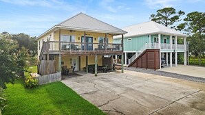 A two-story house with a covered patio and a separate garage. - Bear Point 3BR House Orange Beach Bring Your Boat! (Orange Beach)