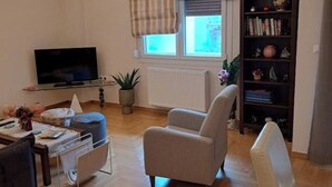 A living room with a television, a bookshelf, and a window with curtains. - Athenian Center Athens Kolonaki (Athina)