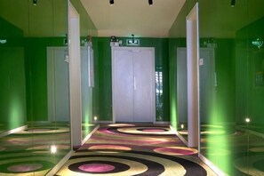 Un pasillo con una pared verde, piso estampado y una puerta doble al final.