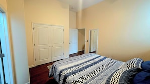 Quarto com cama, duas portas e corredor.