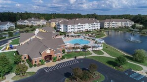 A residential complex with a swimming pool, a parking area, and a lake.