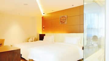 A hotel room with a large bed, a bedside table, and a glass partition wall.