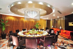 A round dining table with chairs, a chandelier, and a red sofa in a hotel room. - Shaanxi Iron and Steel Building (Xi'an)