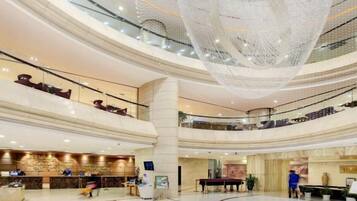 A multi-level hotel lobby with a large chandelier, a reception desk, and a seating area.
