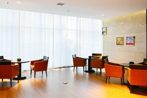 A hotel lobby with a wooden floor, orange chairs, and a large window with sheer curtains. - Shaanxi Iron and Steel Building (Xi'an)