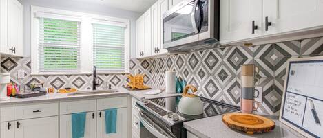 A modern kitchen with white cabinets, a microwave, and a gas stove.
