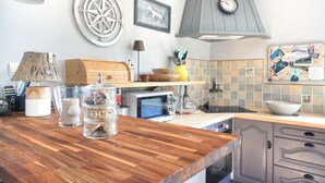 A kitchen with wooden countertops, a microwave, a stove, and a clock on the wall. - La Maison Merlin - Maison avec piscine, Sénoville (Sénoville)