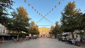 Une vaste place avec un bâtiment central, entourée d’arbres et agrémentée d’espaces de repos en plein air.