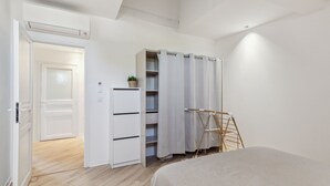 Une chambre à coucher comprenant un lit, une armoire, une étagère et un étendoir.