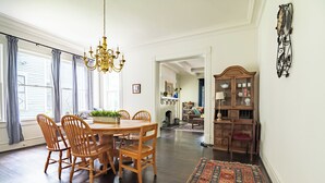 Zona pranzo con tavolo e sedie in legno, un lampadario e un tappeto decorato.